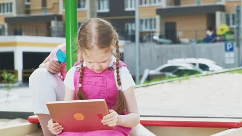 Children use a computer tablet, walk on the playground Video stock 107958762