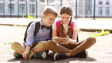 Children  using smartphone together browsing online. The children are sitting ne Stock Footage 82469611