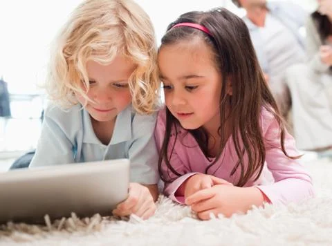 Children using a tablet computer while their parents are in the background Stock Photos