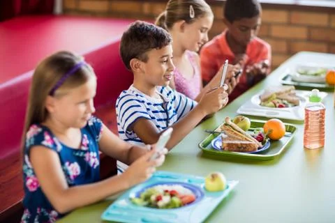 Children using technology during lunch Stock Photos
