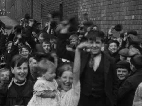 Children walk four abreast down a hill next to brick wall, United Kingdom, 1901 Stock Footage 132022178