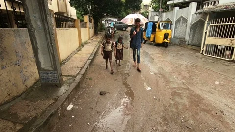 Children walk to school in rain Stock Footage 94904038