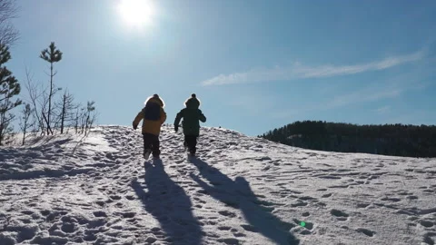 Children walking down snowy mountain on sunny winter day Stock Footage 302823111
