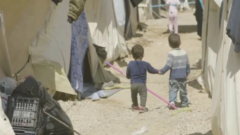 Children walking on a narrow passage between tents with a floor wiper Stock Footage 77446570