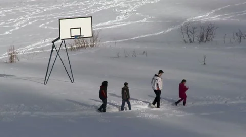Children walking in the snow at lonely playground Stock Footage