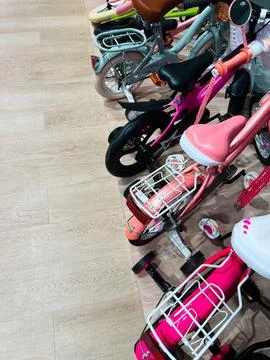 Children's bicycles lined up inside a store with wooden flooring Stock Photos