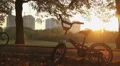 Children's bike left in park standing in sunset rays, happy childhood memories HD Footage