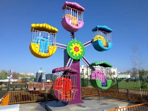 Children's carousel in the form of a sun with five beams with seats for children Stock Photos