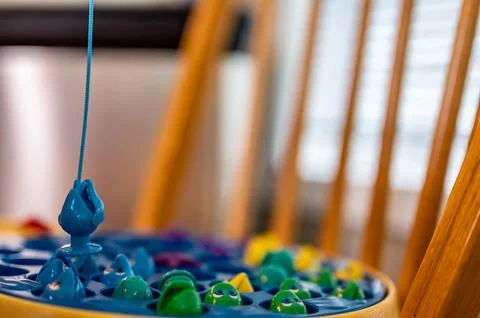 Children's game of using a miniature pole and line lowered into open plastic Foto stock