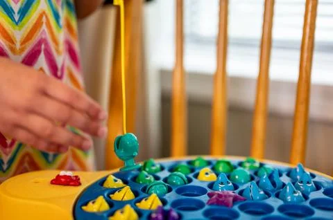 Children's game of using a miniature pole and line lowered into open plastic Foto stock