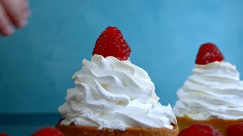 Children's hand puts raspberry on a meringue cake Stock Footage 123611731