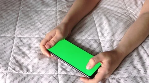 Children's hands are holding a mobile phone with a green screen close-up. Stock Footage 153849415