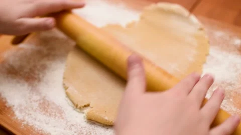 Children's hands close-up roll out the dough for gingerbread with a wooden Stock Footage 142280771