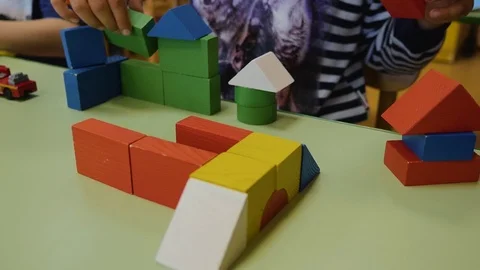 Children's hands collect bright cubes of wood close-up on the table. Logical Stock Footage 113732057