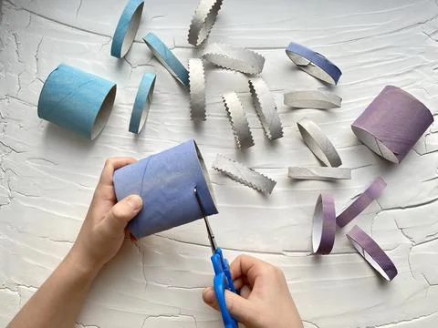 Children's hands cut with scissors, a roll of toilet paper. Stock Photos