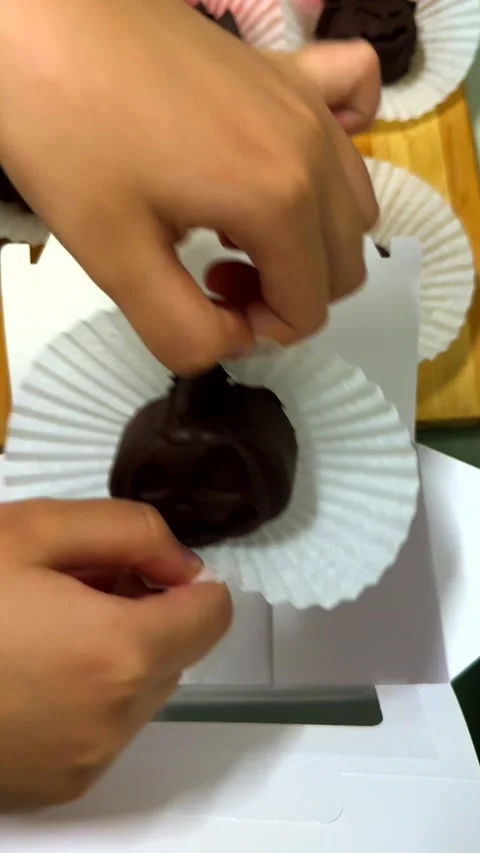 Childrens hands gently place handmade chocolate into a gift box, preparing a Stock Footage 343478443
