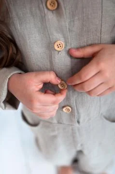 Children's hands hold button close up. Little girl with long hair in jumpsuit Foto stock