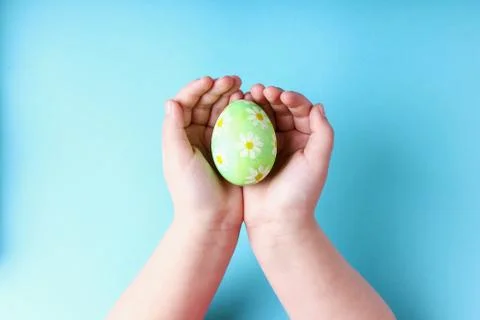 Children's hands hold a decorated Easter egg, on a blue background. Foto stock