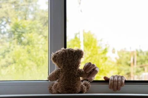 Children's hands hold on to the window from the side of the street and hold a Stock Photos
