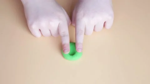 Children's hands interfere with green air plasticine on a beige background. Stock Footage 151346085