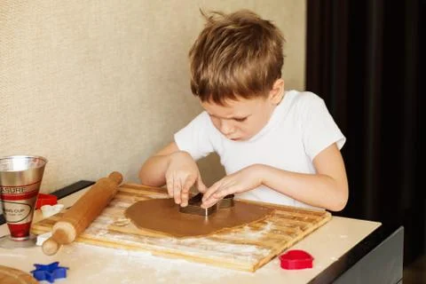 Children's hands make gingerbread. Small boy cutting cookies for Christmas. K Stock Photos