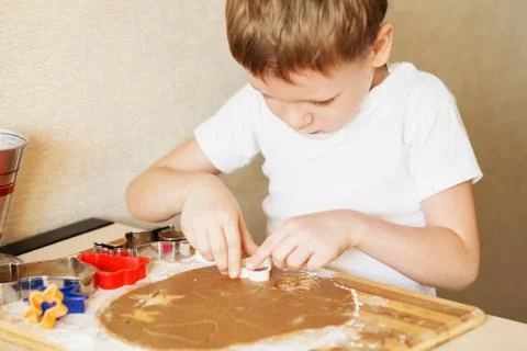 Children's hands make gingerbread. Small boy cutting cookies for Christmas. K Stock Photos