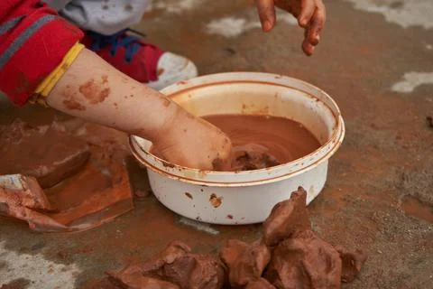Children's hands mold clay inside a bowl. Stock Photos