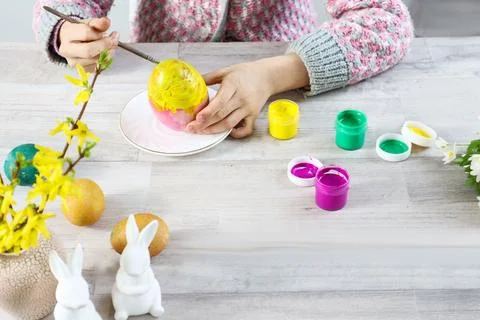Children's hands paint an Easter egg, top view Stock Photos