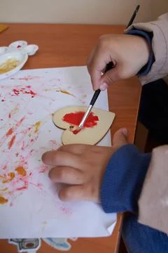 Children's hands with paint mixer and wooden hearts r. valentine's day Stock Photos