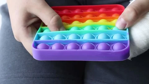 Children's hands play with rainbow pop it antistress. Popular multi-colored toy Stock Footage 155413758