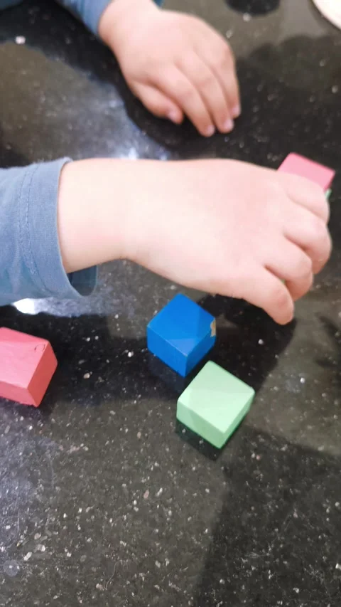 Childrens hands playing with colorful cubes on a black marble tabletop Stock Footage 310698080