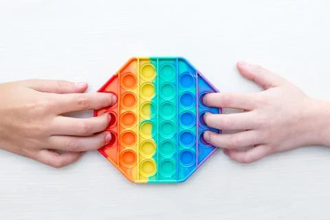 Childrens hands playing with sensory pop it toy. Sensory toy develops fine motor Stock Photos