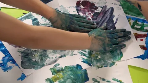 Children's hands smeared with paint leave an imprint on the paper, close-up. 動画素材 167966232