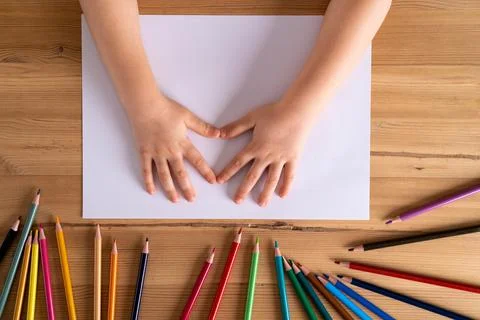 Children's hands on the table and a white sheet of paper and colored pencils, Stock-Fotos