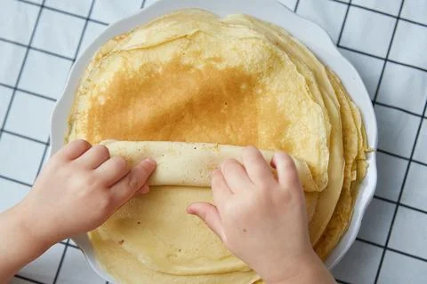 Children's hands take a pancake from a stack. top view Stock Photos
