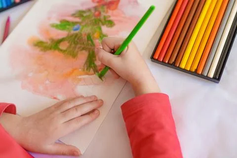 Children's hands on a white table drawing Christmas tree with colorecd pencil Stock Photos