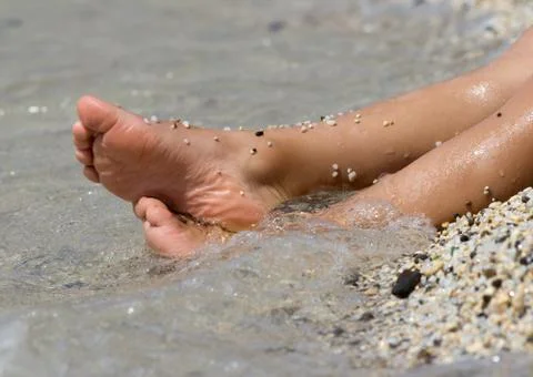 Children's legs against a background seashore Stock Photos