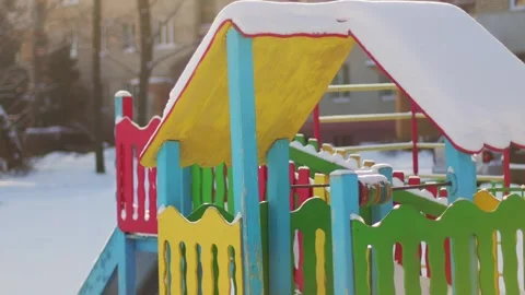 Childrens multi-colored playhouse with a cap of snow on the playground in winter Видео 291779543