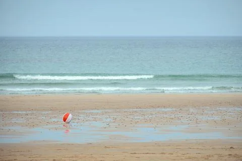 Children's multi-coloured ball rolling in the wind on a sea beach Stock Photos