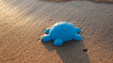 Children's plastic toy on the beach. Concept of relaxing at sea. Camera pan. Stock Footage 114994443