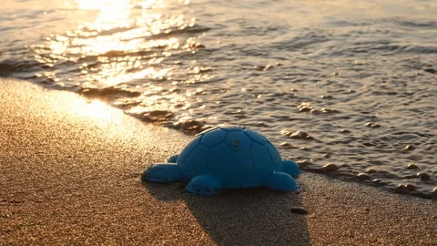 Children's plastic toy on the beach. Concept of relaxing at sea. Camera pan. Stock Footage 114995124