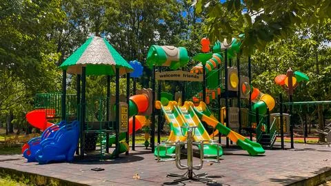 A children's play complex surrounded by greenery and trees Stock Photos