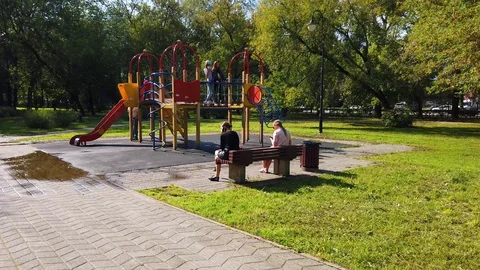 Children's playground in the city park. Parents look after the children. Stock Footage
