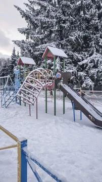 Children's playground covered with snow. Empty swings and slides. Фото