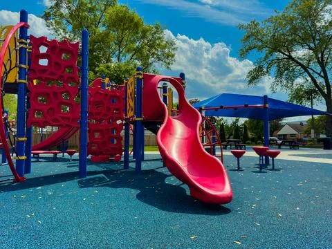 Children's playground features a red slide and a play structure surrounded by Stock Photos