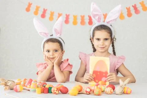 Childrens at the table decorated for Happy Easter. Girl and boy have fun getting Stock Photos