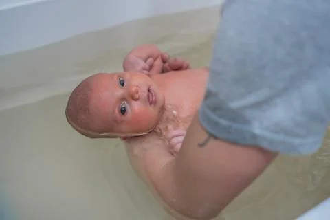 Children's therapy in a warm bath. Bathing baby in the baby bath. Baby massage Stock Photos