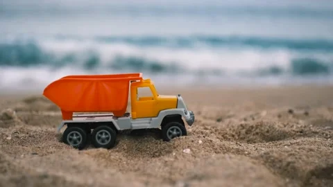 A children's toy car stands on the sand on the beach, sea waves are in the Stock Footage 220732016