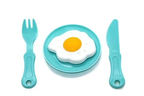 Children's toy plastic tableware: plate with fried eggs, fork and knife. Serv Stock Photos