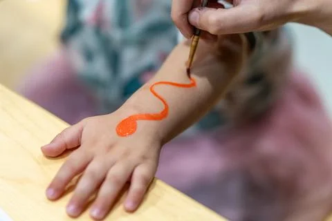 Child's arm getting temporary snake design painted Fotos Stock
